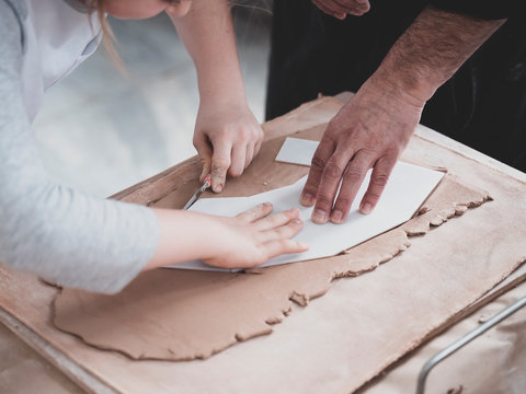 Craftsman teaching girl how to cut clay making vase crafts hobby workshop