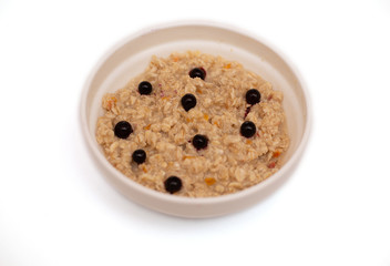 porridge for the whole family with berries for a healthy diet on a white background in a white bowl for design with blue berries