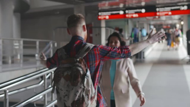 Happy young man and senior woman embracing at train station. Son welcoming mother after trip.