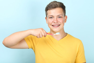 Young man with toothbrush on blue background