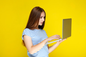 Young woman using laptop computer on yellow background