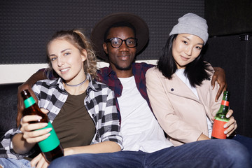 Fototapeta premium Portrait of handsome African man posing with two young women in nightclub, shot with flash
