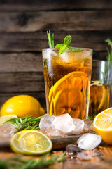 Lemonade with ice and mint on old wooden boards. Ice tea with lemon and lime on a wooden table, close up.