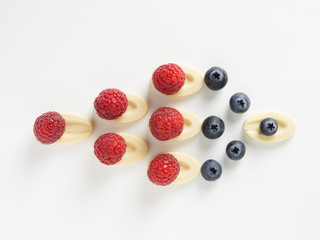 frambuesas y arándanos sobre chocolate blanco colocado geométrico