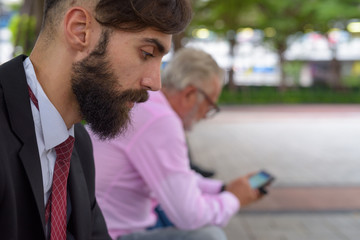 Two multi ethnic bearded businessmen together around the city