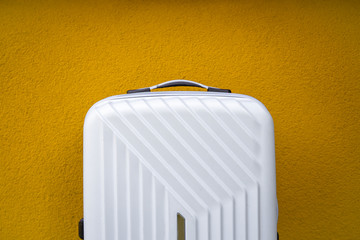 White travel bag on a yellow wall background.
