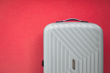 White travel bag on red wall background; travel and object concept.