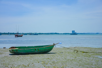 Naklejka premium Fishing boat parked on the beach,Fishing boat parked on the seashore,Small fishing boat parked and moored on the beach at low tide. Boat and anchor at the beach in summer vacation. Sunny day.