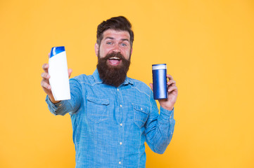 Good choice. Happy hipster hold shampoo and conditioner yellow background. Brutal hipster with hair...