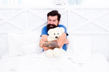 Man hug soft toy relaxing in bed. Make surprise concept. Gift for spouse. Cute teddy bear toy. Softness tenderness. Playful adult. Cute and romantic. Bearded hipster play toy. Valentines day gift