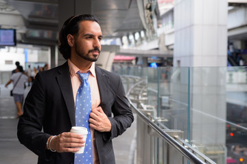 Young bearded Indian businessman relaxing around the city