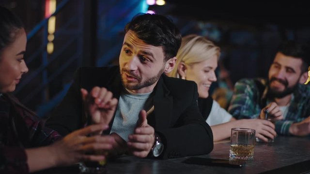 Nice atmosphere in a glamorous bar young people ladies and guys enjoying the time together drinking some cocktails feeling relaxed they chatting concentrated with each other