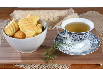 Brazilian snack on the table with cup of tea, cheese biscuit, vase with flowers on the gradient background with space for text