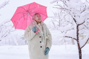 older woman with red umbrella in the snow