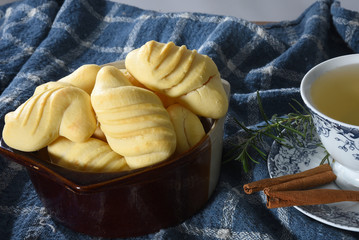 Brazilian snack on the table with cup of tea, cheese biscuit, vase with flowers on the gradient background with space for text