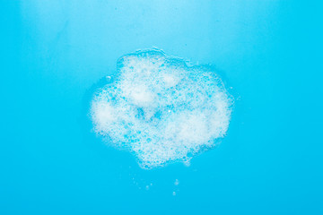 Soap foam on a blue background. Cleaning concept, housekeeper. Flat lay, top view