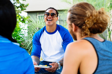 Happy friends enjoying summer BBQ party poolside at apartment complex. 