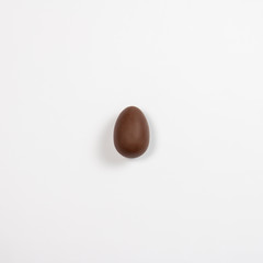 Easter chocolate egg on a light background. Easter concept, easter treats. Square. Flat lay, top view