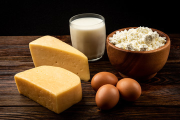 Dairy products. Milk, cottage cheese and cheese on dark wooden background.