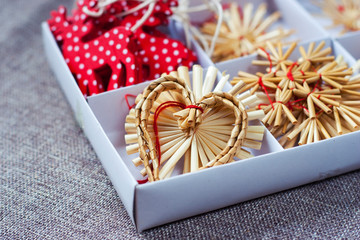 Box of ornaments made of straw. Straw heart