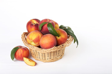 Fototapeta na wymiar Fresh peaches in basket on white wooden table