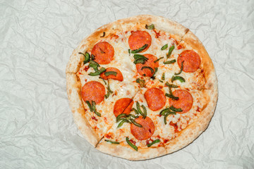 Delicious hot fresh Pepperoni pizza with mozzarella cheese and salami. On light paper background