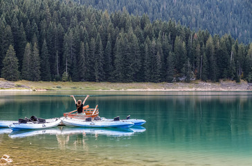 Fototapeta na wymiar Black lake in Durmitor national park in Montenegro, boats on the lake reflected in water. Freedom and tranquility.
