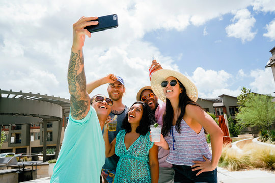 Friends at summer party laughing and taking selfie photo with cell phone