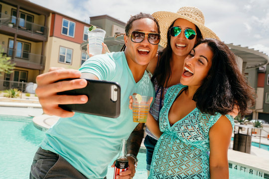 Friends at summer party laughing and taking selfie photo with cell phone