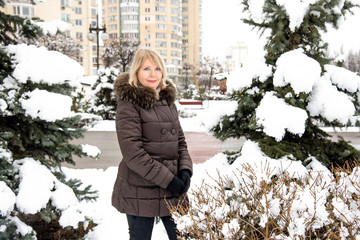 Portrait of happy mature woman in snowy park on winter vacation. Сlose up рortrait of a mature woman in winter