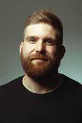 Fabulous at any age. Close up portrait of sweet charismatic muscular 30-year-old man with red hair posing over light gray background. Perfect haircut. Rocker, biker, hipster style. Studio shot