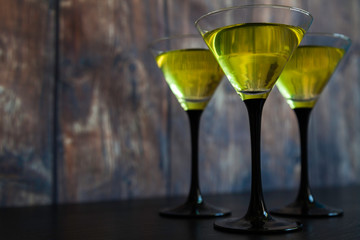 three yellow cocktails on old wood