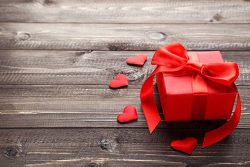 Gift box with ribbon and hearts on wooden table