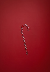 One striped candy cane on red background. Cristmas lollipop