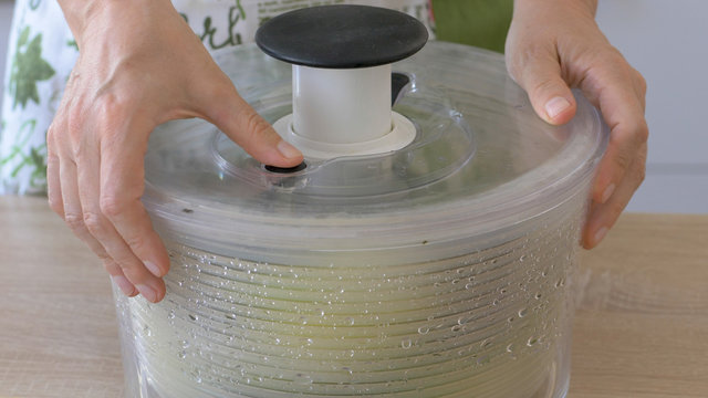 Woman Drains Lettuce From The Water In A Salad Spinner