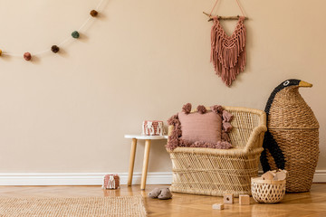 Stylish and cute scandinavian decor of newborn baby room with natural toys, hanging decor balls, macrame, sofa, plush animals and accessories. Beige walls. Interior design of kid room. Home staging.