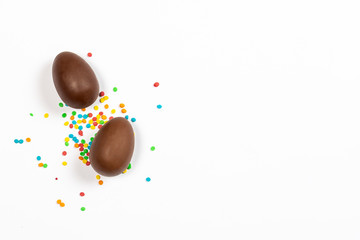 Easter chocolate eggs and colorful decorations on a light background. Easter concept, easter treats. Banner. Flat lay, top view