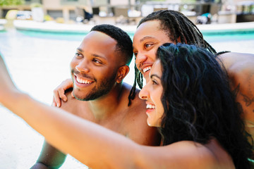Friends in pool taking selfie with camera phone
