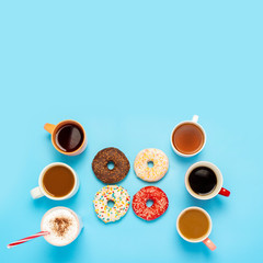 Obraz na płótnie Canvas Tasty donuts and cups with hot drinks, coffee, cappuccino, tea on a blue background. Concept of sweets, bakery, pastries, coffee shop, meeting, friends, friendly team. The square. Flat lay, top view