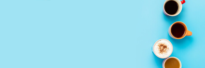 Cups with hot drinks, coffee, cappuccino, coffee with milk on a blue background. Concept coffee shop, meeting friends, breakfast with friends, friendly team. Banner. Flat lay, top view