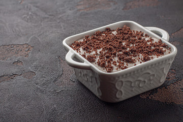 Tasty pudding with chocolate crumble cookie in ceramic form. Dark.