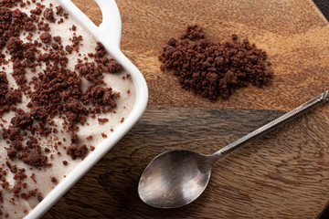 Tasty homemade pudding with chocolate crumble cookie in ceramic plate on wooden background.