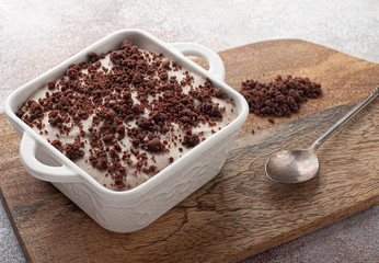 Tasty homemade pudding with chocolate crumble cookie in ceramic plate on wooden background.
