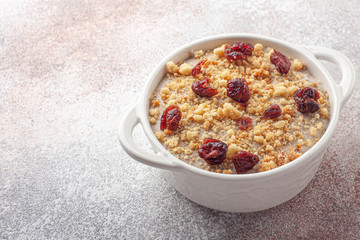 Tasty homemade pudding with cranberry and crumble cookie in ceramic plate on wooden background.