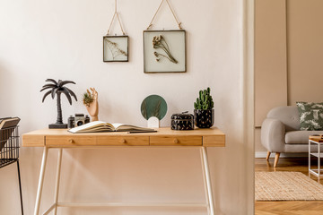 Interior design of scandinavian open space with mock up photo frames, wooden desk, gray sofa, cacti, books office and personal accessories.  Stylish neutral home staging. Beige walls.  Template.