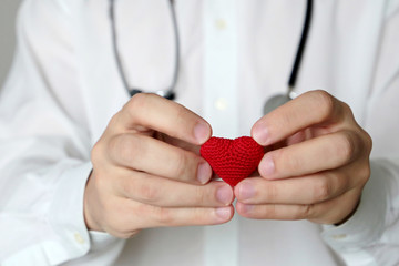 Cardiology and health care, doctor holding red knitted heart in hands. Concept of cardiologist,...