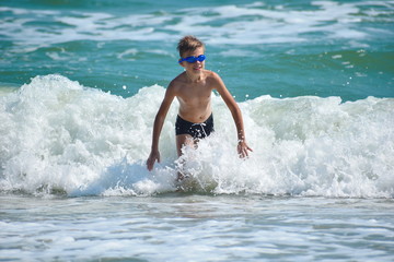 Child boy jumping on sea waves. Happy child in the ocean.