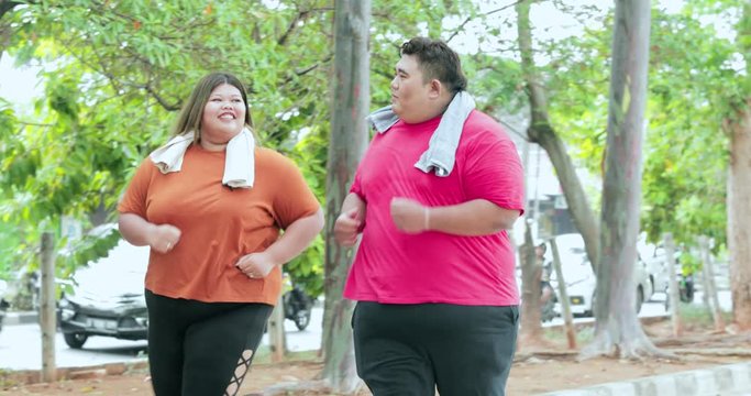 Young obesity couple running together at the park while talking to each other. Shot in 4k resolution