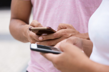 Closeup shot of hands texting on modern phones. Cropped shot of young people using smartphones. Technology concept