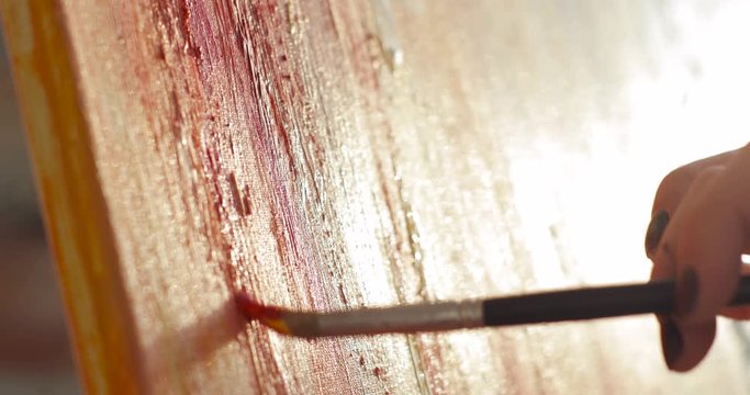 Creative artwork of young talanted painter. Woman paintress is painting abstract picture using brush on canvas, hand closeup. Workflow process of drawing multicolor picture in modern art studio.